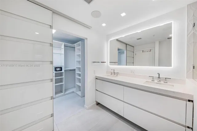 a bathroom with a granite countertop sink a toilet a large mirror and shower