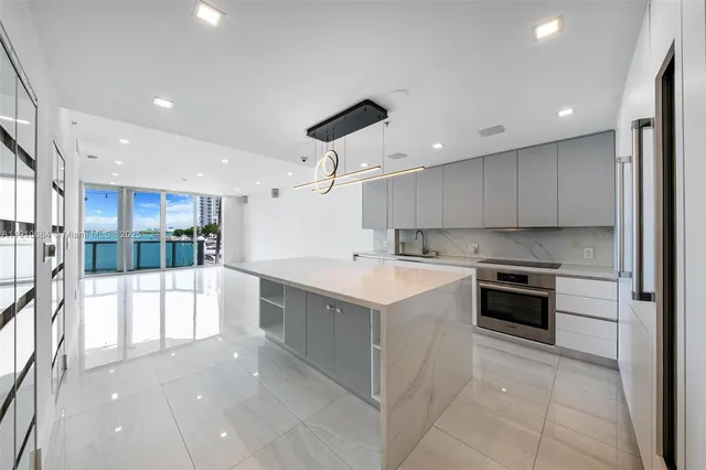 a large white kitchen with stainless steel appliances a large counter top a stove and a refrigerator