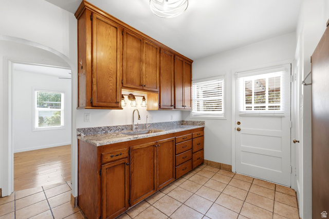 1925 South Main Street Bountiful, UT 84010 - Photo 13 of 48 Kitchenette featuring wood cabinetry, undermount sink with a gooseneck faucet, light-toned stone countertop, and tile flooring