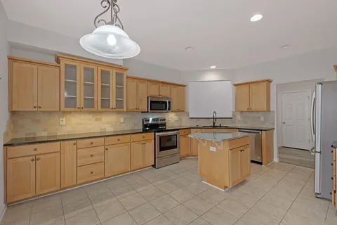 a kitchen with stainless steel appliances granite countertop a stove top oven a sink dishwasher a dining table and chairs with wooden floor