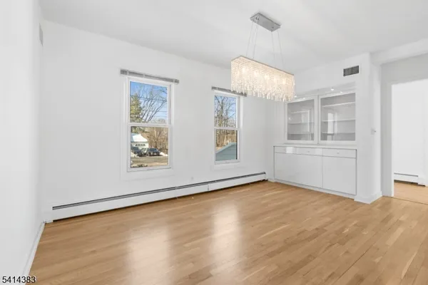 an empty room with wooden floor cabinet and windows