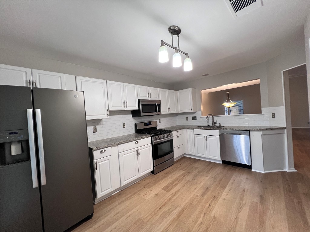 1518 White Oak Loop Round Rock, TX 78681 - Photo 3 of 17 a large kitchen with cabinets wooden floor and stainless steel appliances