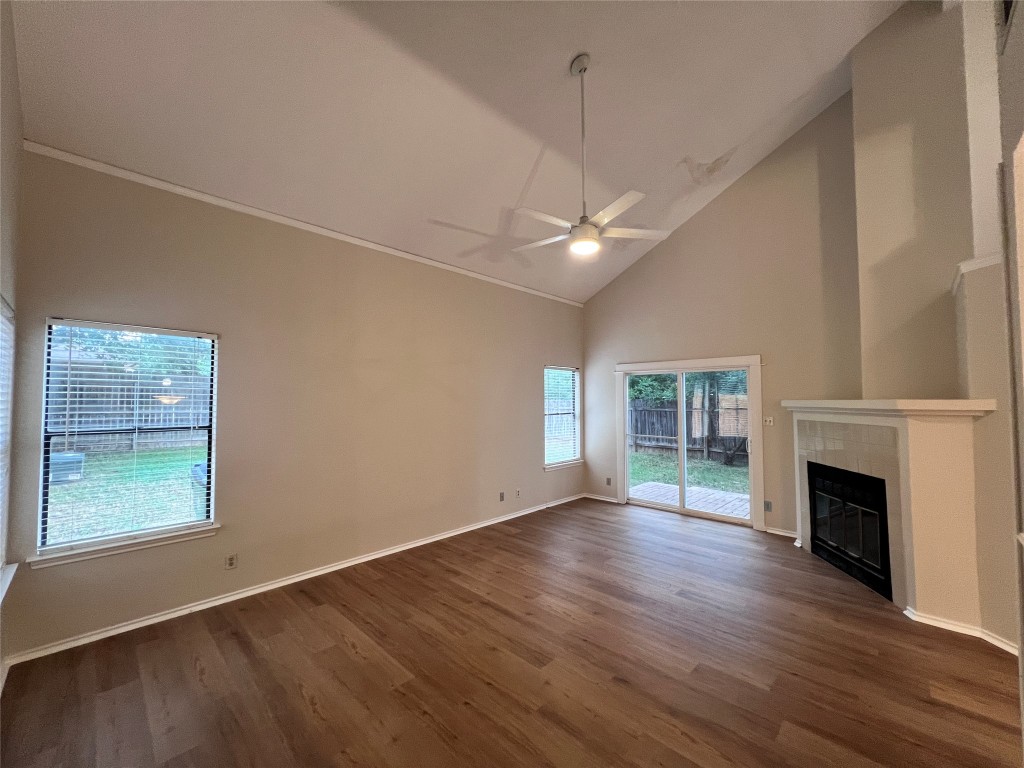 1518 White Oak Loop Round Rock, TX 78681 - Photo 9 of 17 an empty room with wooden floor a fireplace a ceiling fan and windows