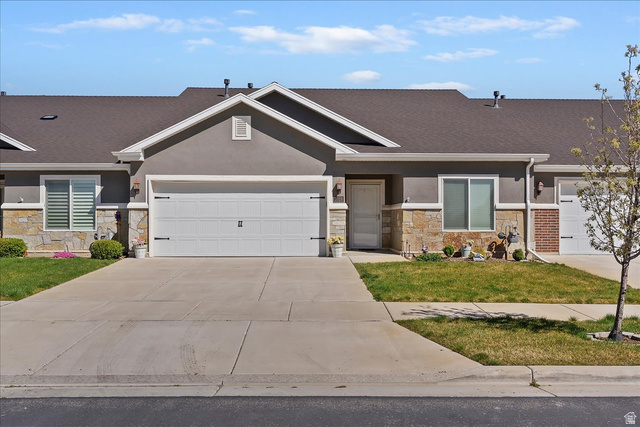 2028 West Grace Way Layton, UT 84041 - Photo 2 of 36 View of front facade featuring stone siding, an attached garage, concrete driveway, a front lawn, and stucco siding