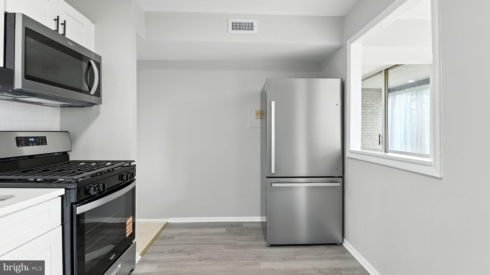 8693 Greenbelt Road, Unit 202 Greenbelt, MD 20770 - Photo 24 of 40 a kitchen with stainless steel appliances granite countertop a refrigerator stove and microwave