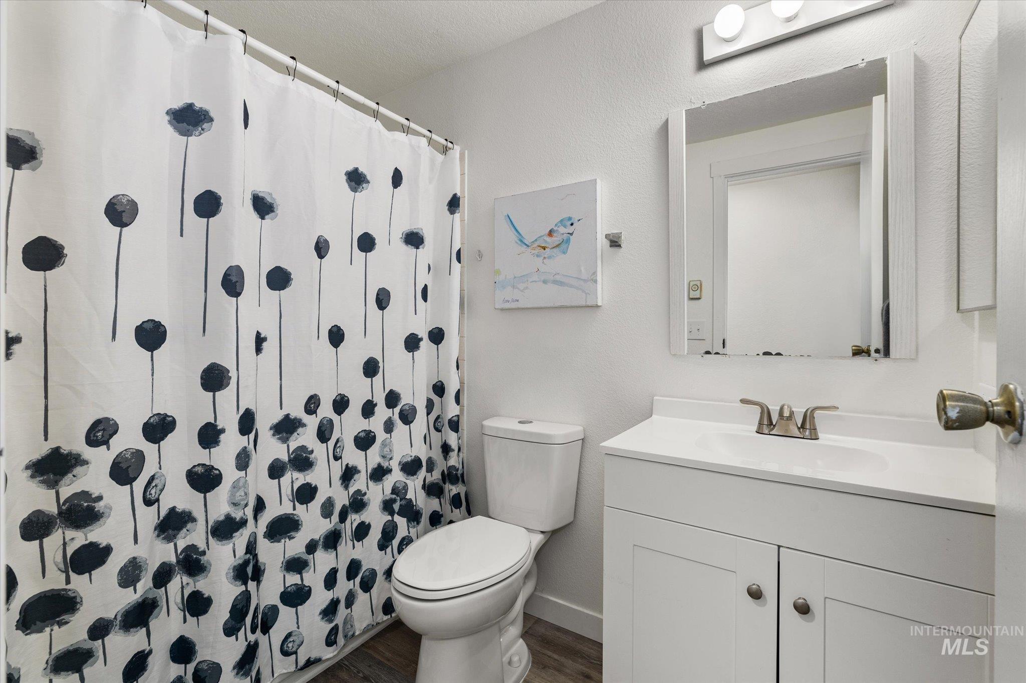 419 West Logan Street Caldwell, ID 83605 - Photo 32 of 50 Full bath with vanity, a shower with curtain, dark wood-style floors, and a textured wall
