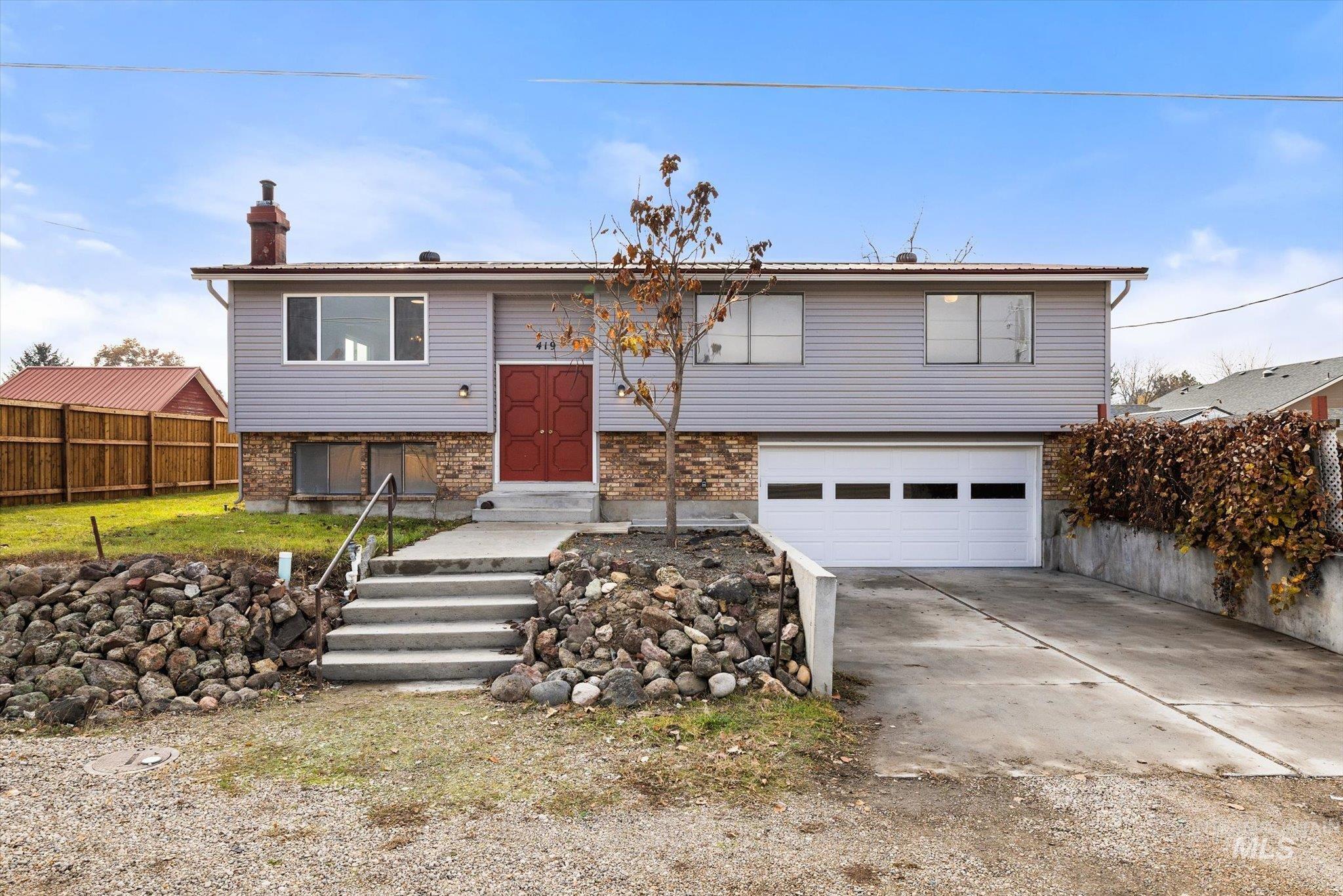 419 West Logan Street Caldwell, ID 83605 - Photo 49 of 50 Bi-level home with brick siding, a chimney, concrete driveway, and an attached garage