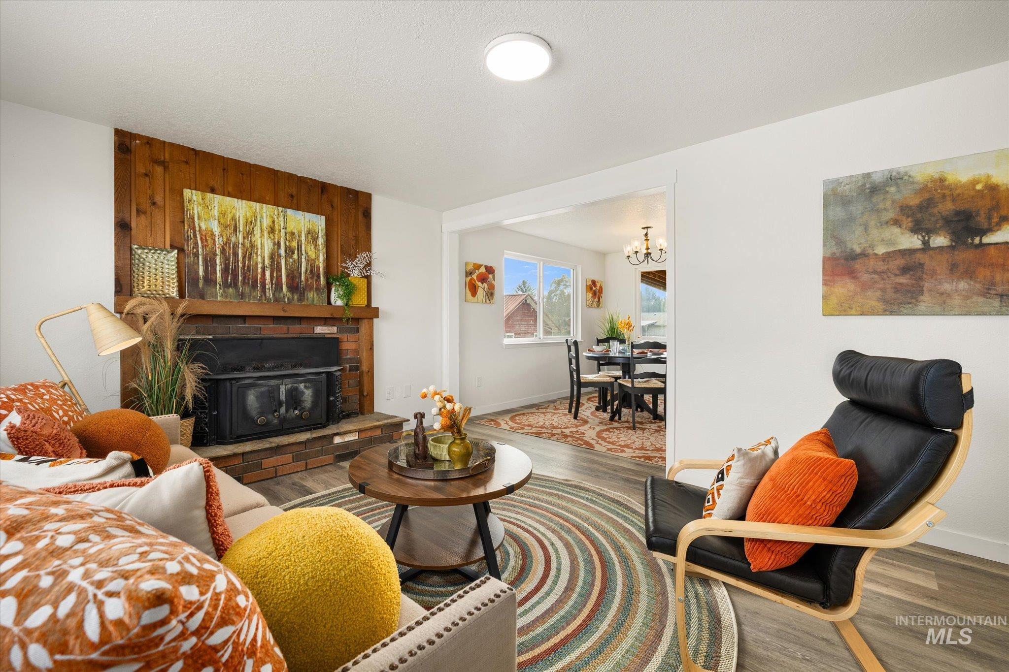 419 West Logan Street Caldwell, ID 83605 - Photo 10 of 50 Living area with wood finished floors, a brick fireplace, and a chandelier