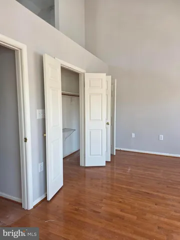 a view of an empty room with wooden floor & closet