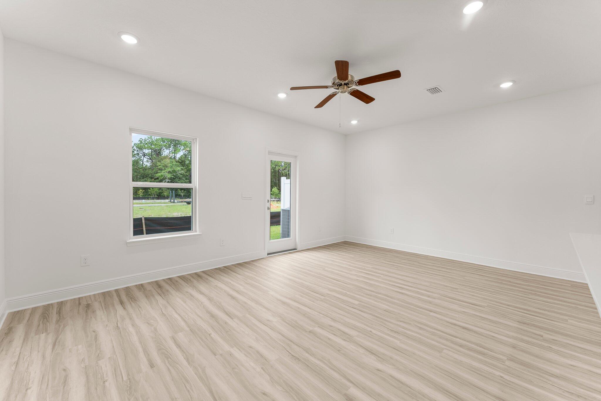 44 Hawk Street Santa Rosa Beach, FL 32459 - Photo 19 of 34 an empty room with wooden floor a ceiling fan and windows
