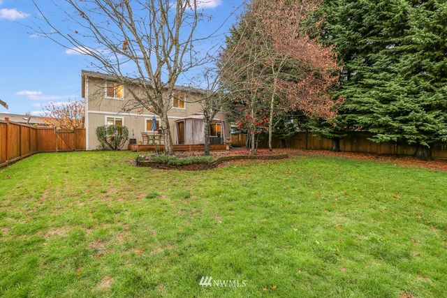 a view of a house with a big yard and large trees