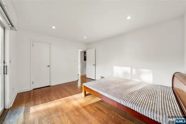 a spacious bedroom with a bed and wooden floor