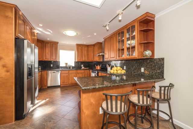 a kitchen with stainless steel appliances granite countertop a stove a sink and a refrigerator