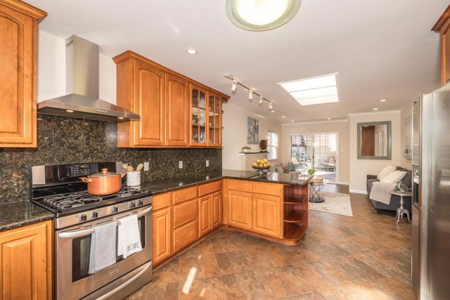a kitchen with stainless steel appliances granite countertop a stove a sink and a refrigerator