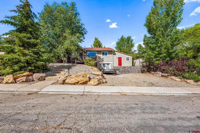 a view of a white house with a road and plants