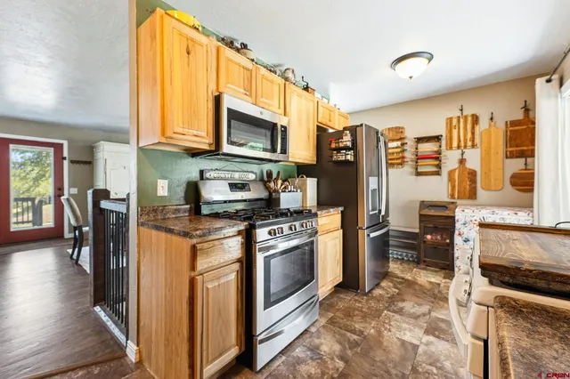 a kitchen with stainless steel appliances granite countertop a stove top oven a sink dishwasher a dining table and chairs with wooden floor