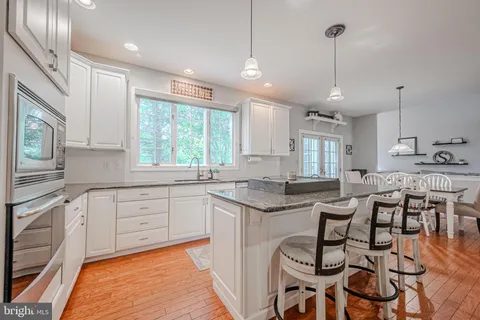 a kitchen with granite countertop lots of white cabinets appliances and furniture