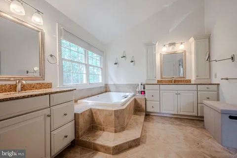 a spacious bathroom with a granite countertop sink mirror and a bathtub
