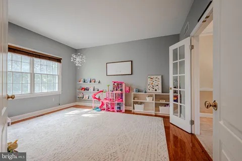 a view of a bedroom with baby bed lounge chair and front door