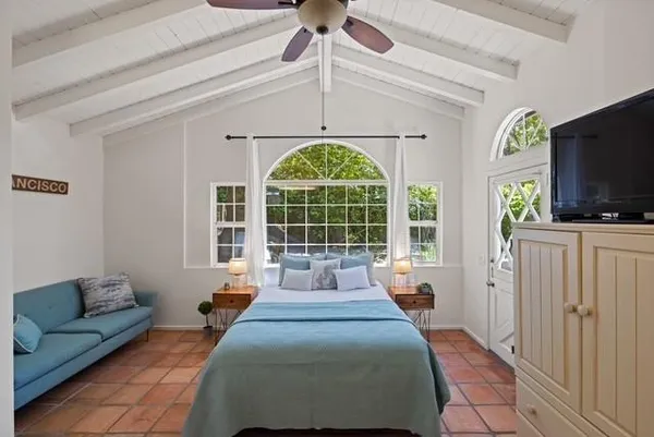 a spacious bedroom with a bed and a flat tv screen on the dresser