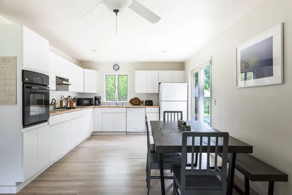 a kitchen with stainless steel appliances granite countertop a dining table chairs refrigerator and microwave