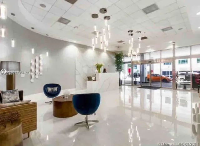 a living room with lots of potted plants and a chandelier