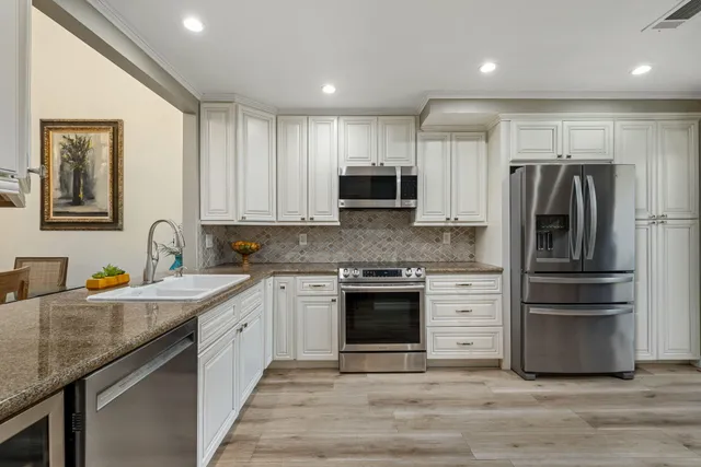 a kitchen with stainless steel appliances granite countertop a refrigerator and a stove top oven