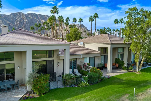 a view of a white house with a big yard and potted plants