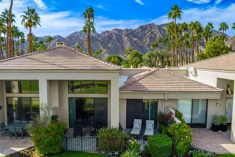 a view of a white house with potted plants and a table