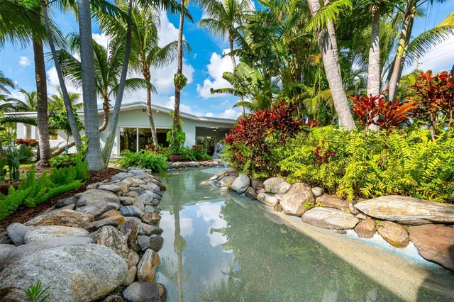 a view of a swimming pool with a garden and palm trees