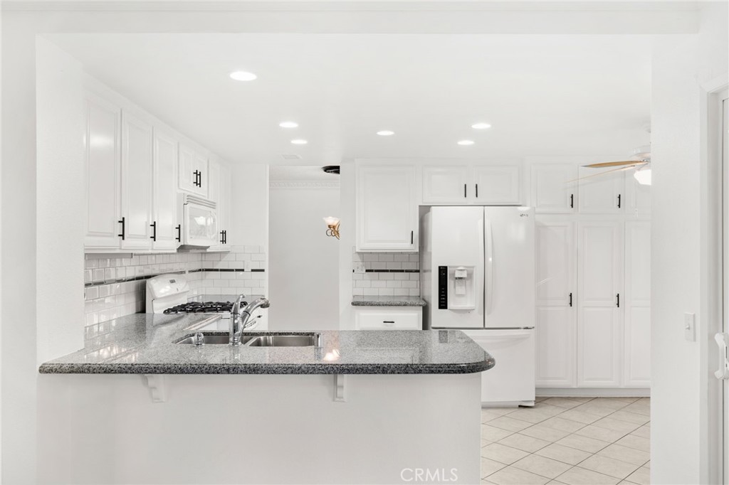 8985 Sage Drive Rancho Cucamonga, CA 91701 - Photo 5 of 49 We are in love with this kitchen complete with granite countertops and decorative tile listelle backsplash! And yes, we are including the fridge too! BONUS!