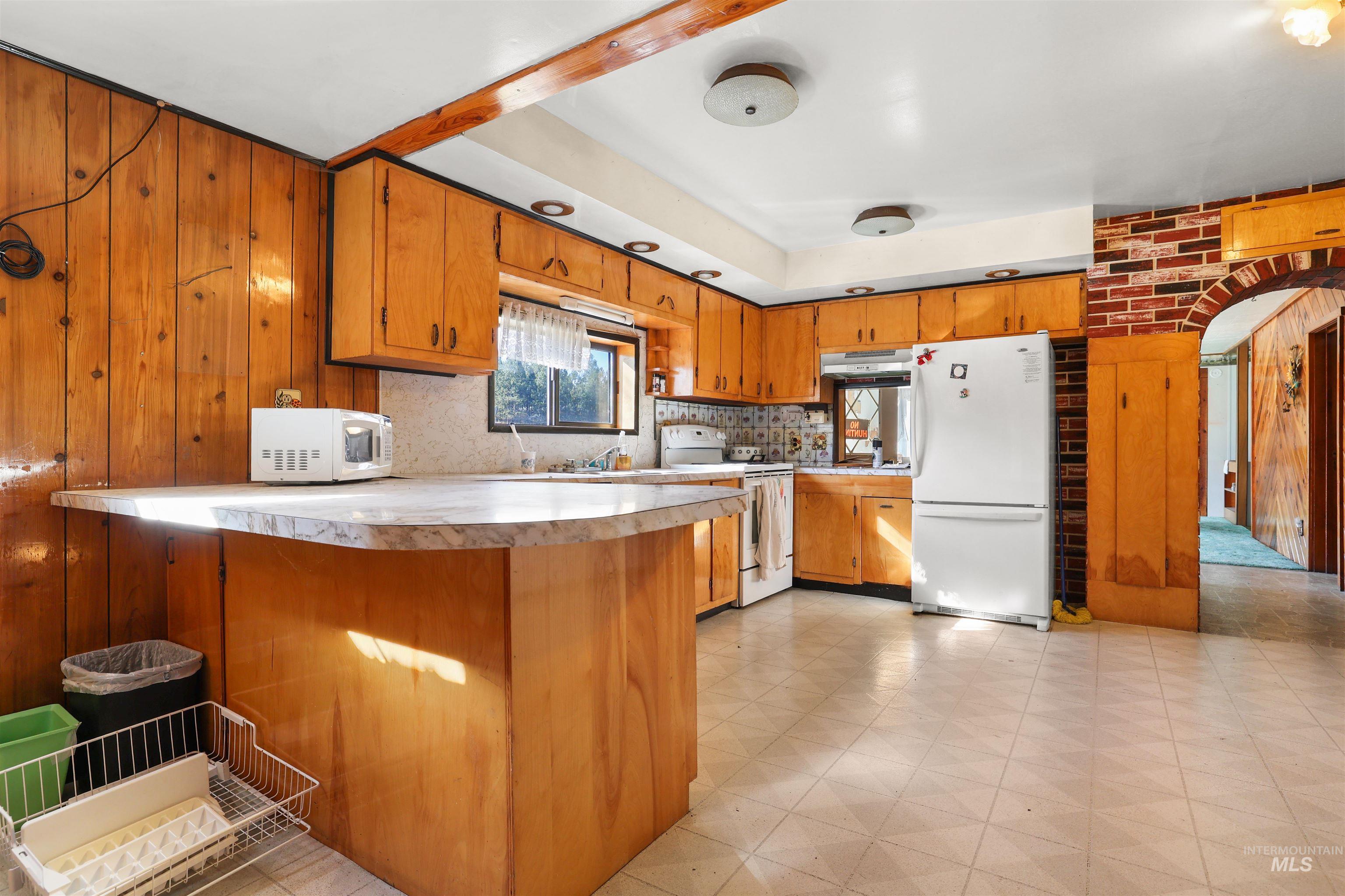 216 Ulmer Road Kooskia, ID 83539 - Photo 17 of 48 Kitchen with arched walkways, a peninsula, wood finish cabinetry, and wood walls