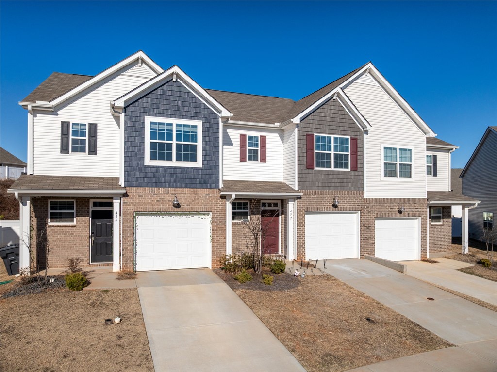 452 Bee Cv Way Pendleton, SC 29670 - Photo 3 of 37 These charming townhomes feature brick and siding exteriors with attached garages under a bright blue sky.
