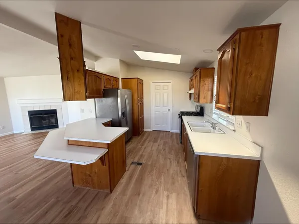 a living room with stainless steel appliances furniture a fireplace and a kitchen view