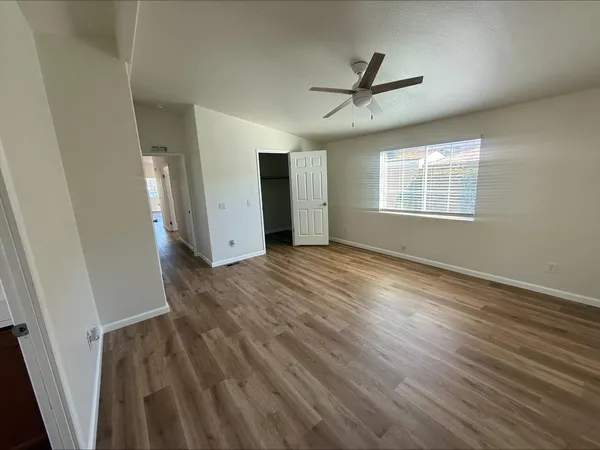 a view of an empty room with wooden floor and a window