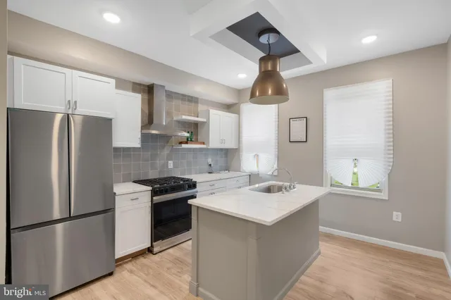 a kitchen with stainless steel appliances granite countertop a sink a stove a refrigerator a center island with wooden floor