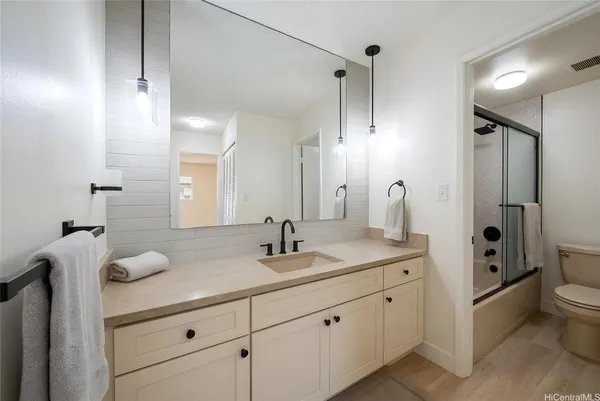 a bathroom with a granite countertop sink mirror vanity and toilet