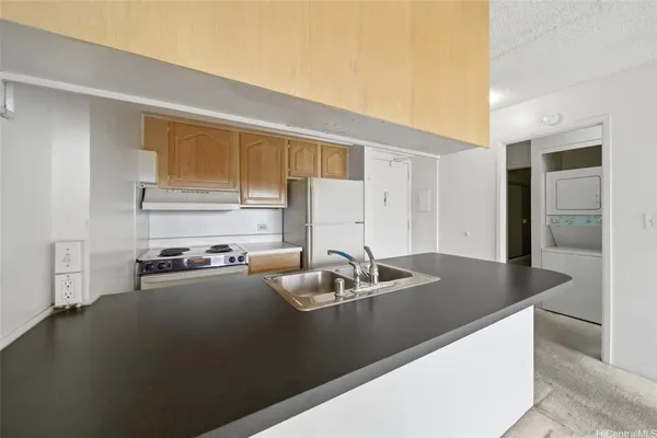 a kitchen with granite countertop a sink a stove and cabinets