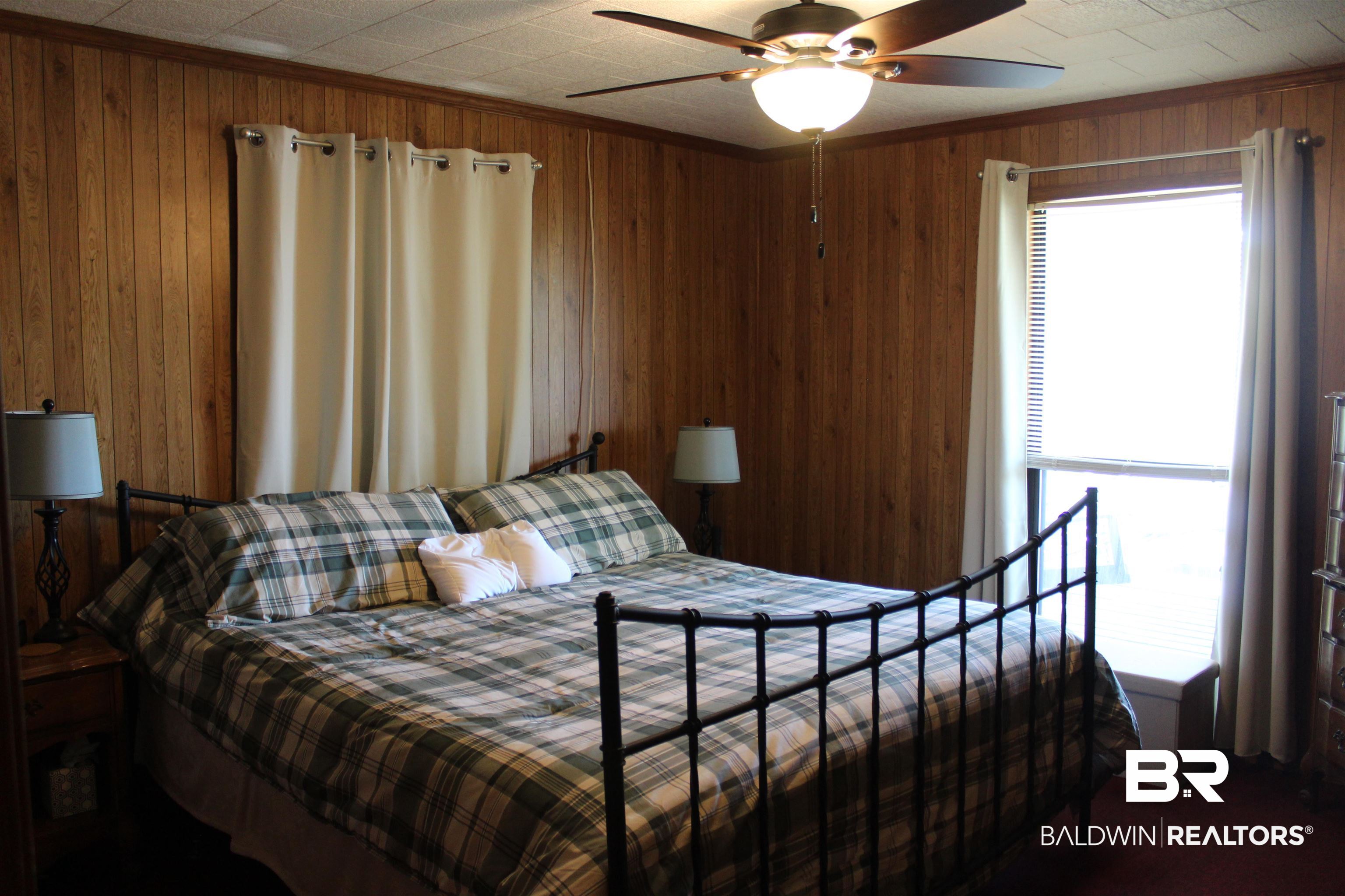 6447 Henderson Road Lowndesboro, AL 36752 - Photo 14 of 22 Bedroom with ceiling fan, wood walls, and crown molding