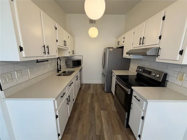 a kitchen with stainless steel appliances a stove a sink and white cabinets
