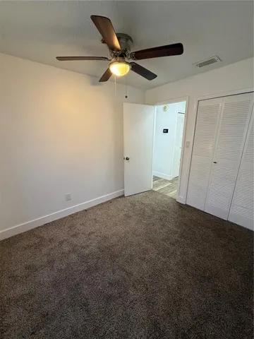 a view of an empty room and chandelier fan