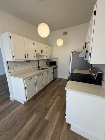 a kitchen with stainless steel appliances a stove a sink and white cabinets