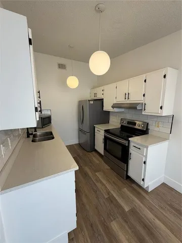 a kitchen with kitchen island granite countertop a sink a counter space and stainless steel appliances