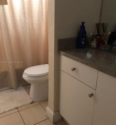a bathroom with a granite countertop sink and a toilet