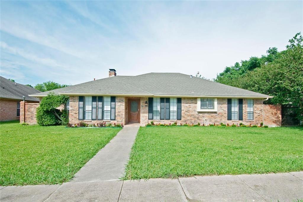 Ranch-style house featuring a front lawn, a chimney, brick siding, and roof with shingles