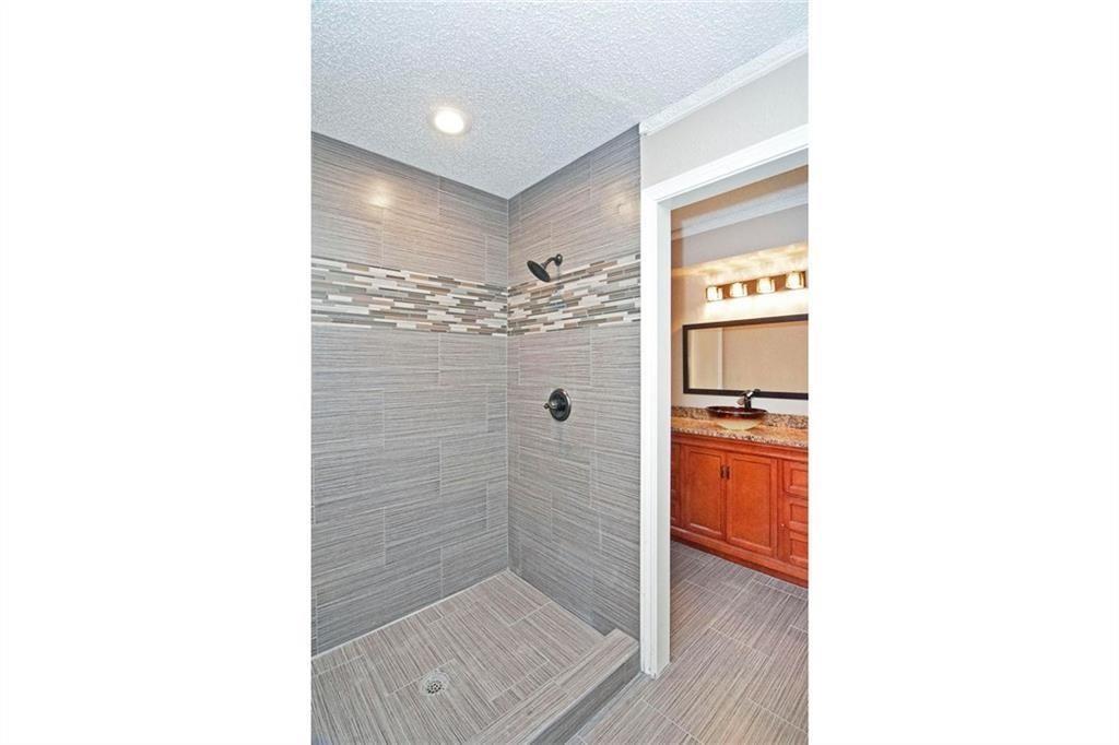 2509 Country Valley Road Garland, TX 75041 - Photo 16 of 17 Full bathroom featuring a tile shower, a textured ceiling, vanity, and recessed lighting