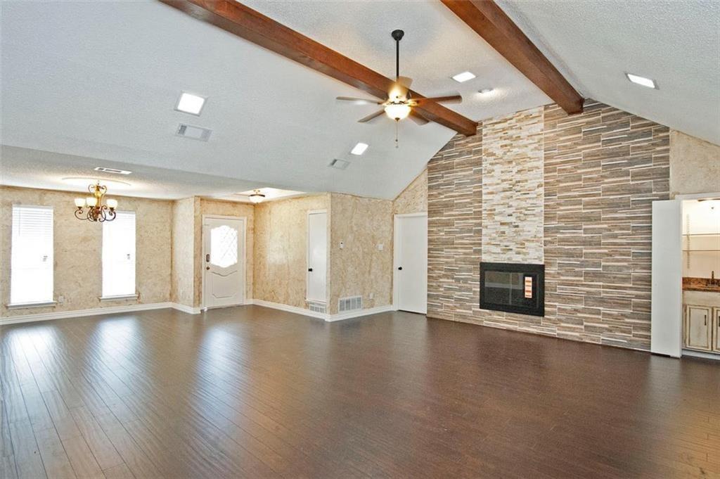 2509 Country Valley Road Garland, TX 75041 - Photo 7 of 17 Unfurnished living room with a textured ceiling, dark wood-type flooring, a tile fireplace, and a ceiling fan