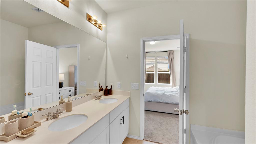 707 Indigo Road Princeton, TX 75407 - Photo 20 of 29 Bathroom featuring a dual vanity with undermount sinks, a large mirror, and a three-light fixture