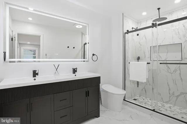 a bathroom with a double vanity sink toilet mirror and shower