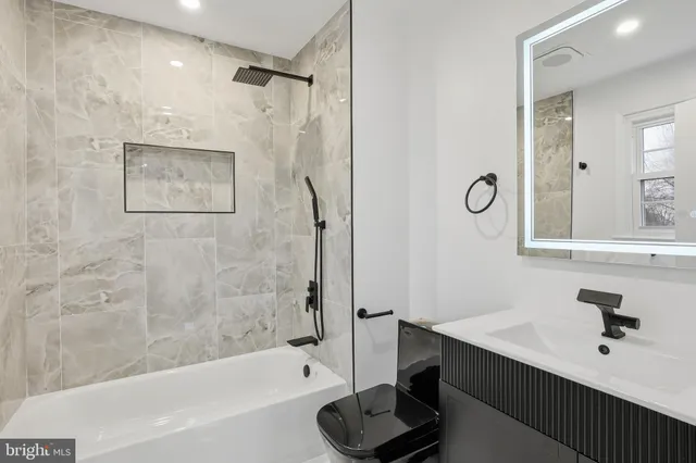 a bathroom with a bathtub shower sink vanity and a mirror